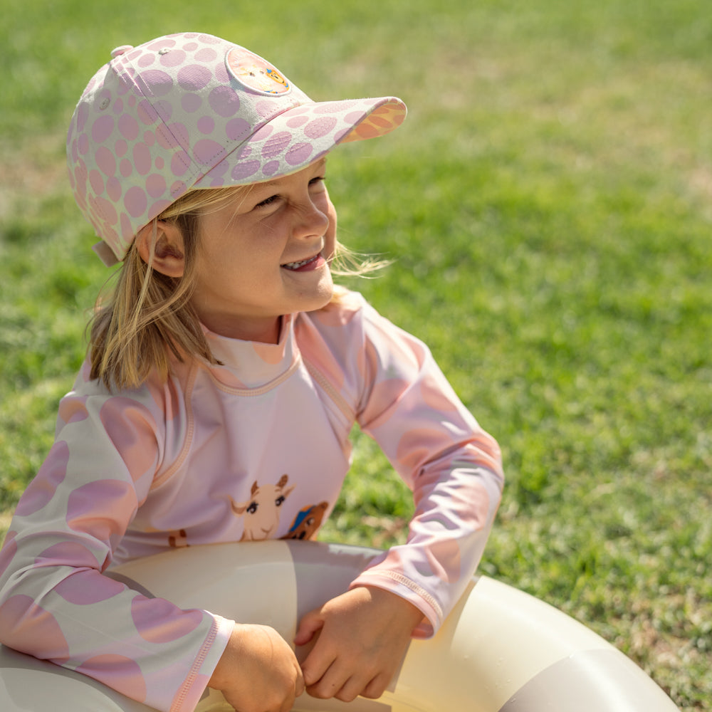 Barn leker i rosa uv-kläder och keps
