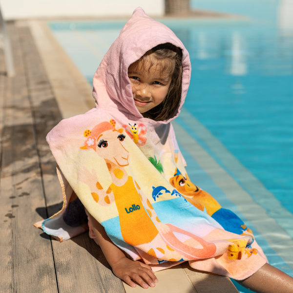 Barn vid poolen i rosa badponcho