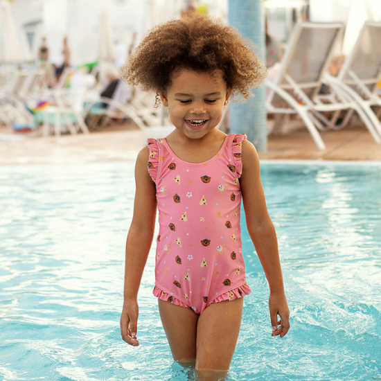 Barn badar i poolen med rosa baddräkt